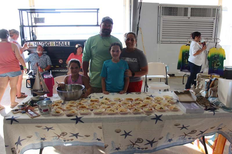 A group of people are standing around a table with food on it.