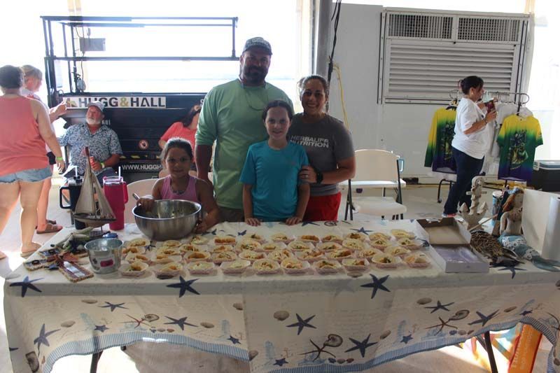 A group of people standing around a table with food on it.