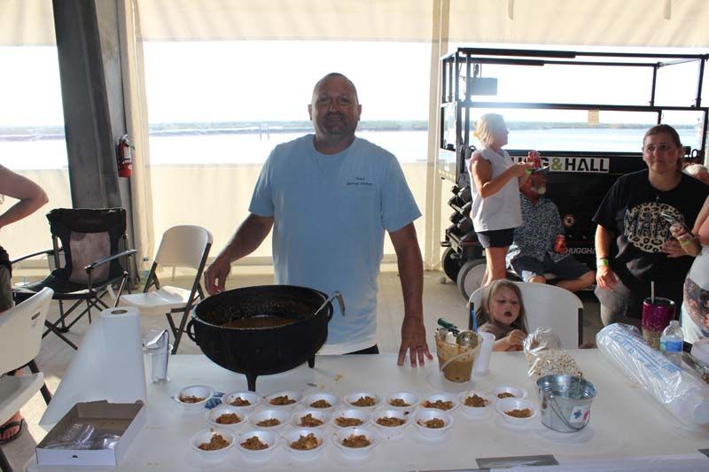 A man is standing in front of a table with food on it.