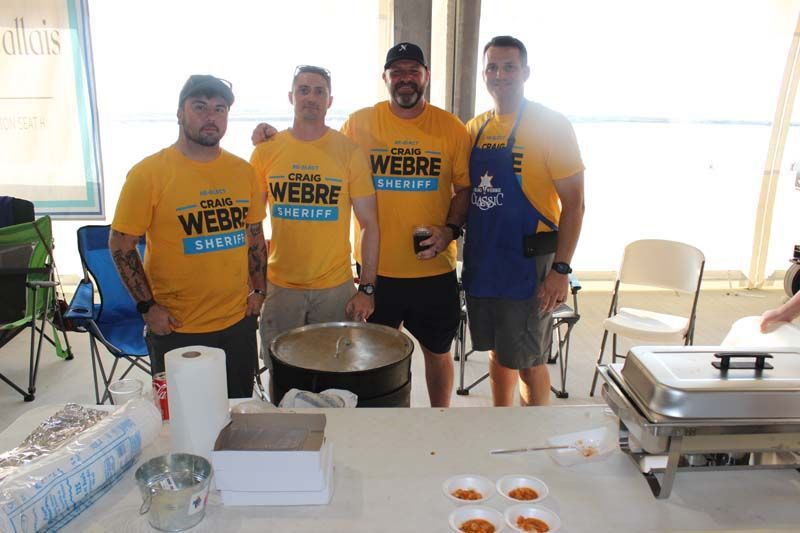 A group of men wearing yellow shirts and aprons are standing around a table.