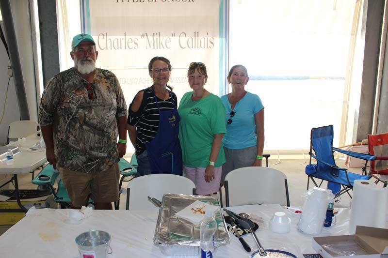 A group of people standing around a table in front of a sign that says charles mike collins
