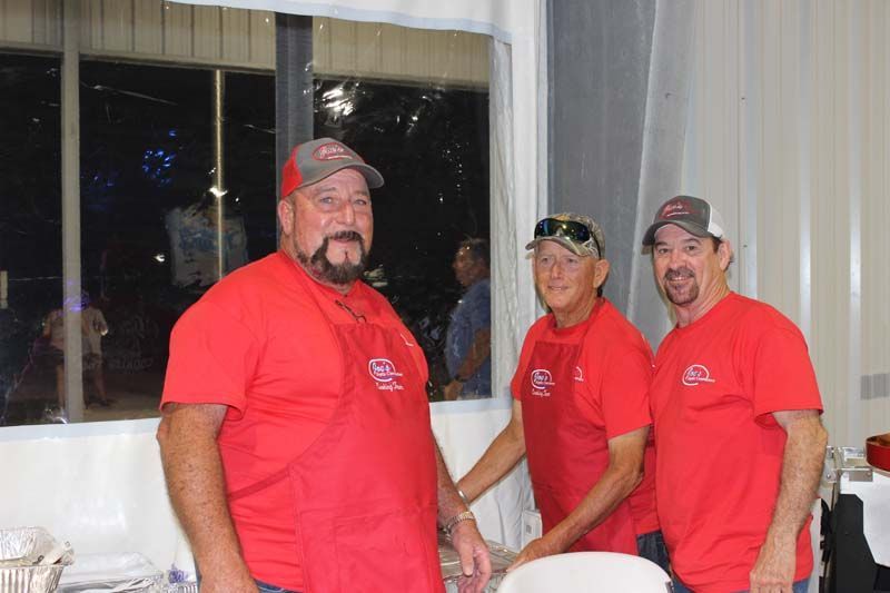 Three men in red shirts are standing next to each other in a room.