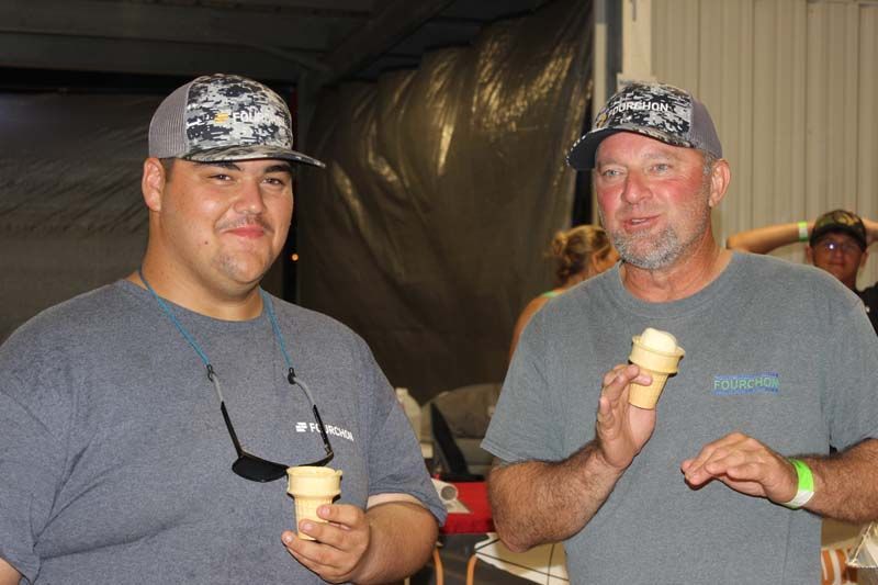 Two men are standing next to each other holding ice cream cones.
