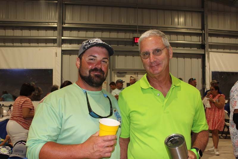 Two men are standing next to each other in a room holding cups.