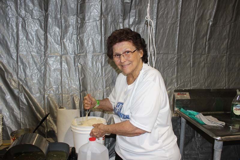A woman in a white shirt is preparing food in a kitchen.