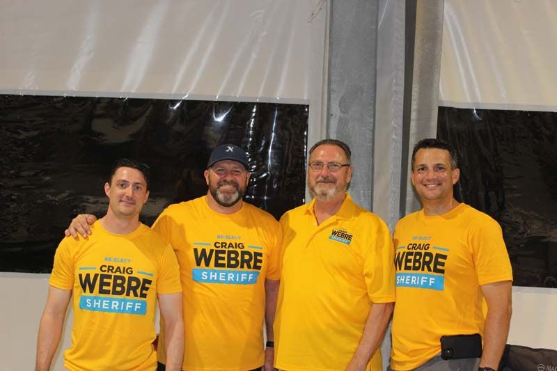 Four men wearing yellow shirts that say webre sheriff are posing for a picture.
