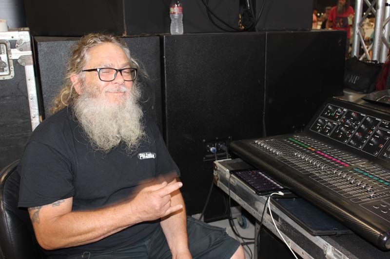 A man with a beard and glasses is sitting in front of a mixer.