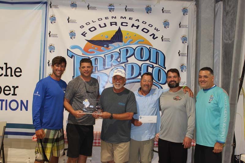 A group of men standing in front of a banner that says fourchon