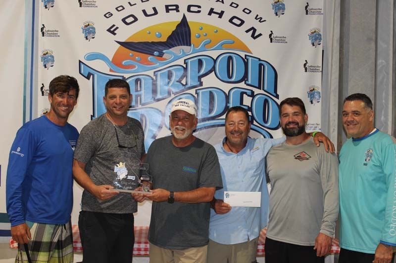 A group of men standing in front of a tarpon dco banner