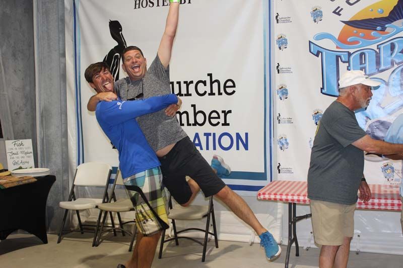 A man is holding another man in his arms in front of a banner that says hurche mber ation