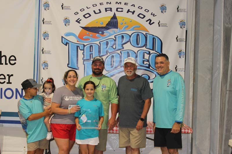 A group of people standing in front of a tarpon open sign.
