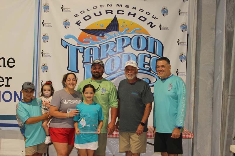 A group of people standing in front of a banner that says tarpon loops.