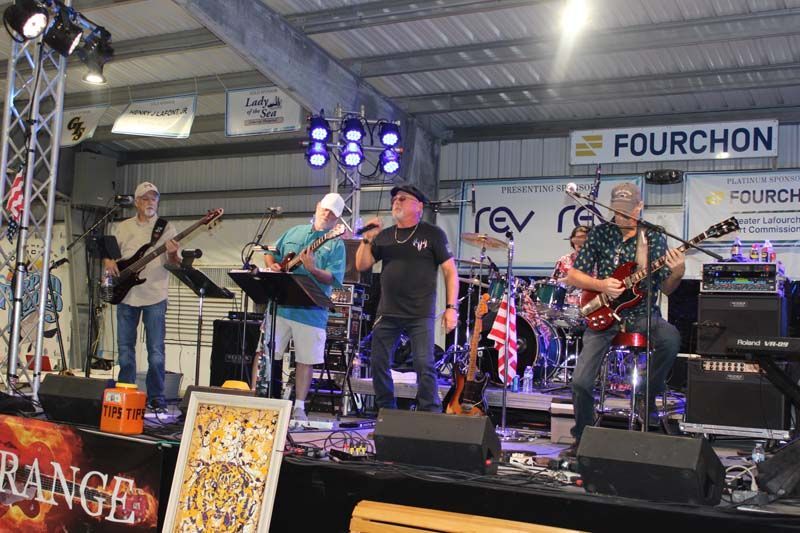 A group of men are playing instruments on a stage in front of a sign that says fourchon