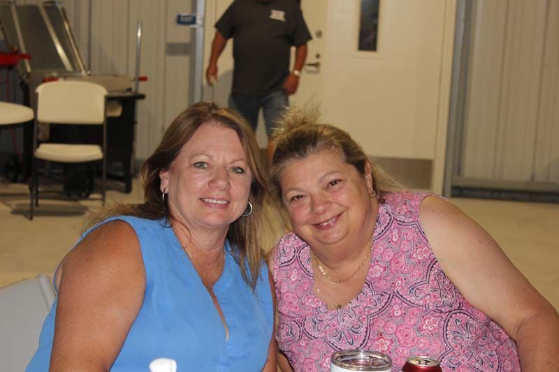 Two women are posing for a picture while sitting at a table.