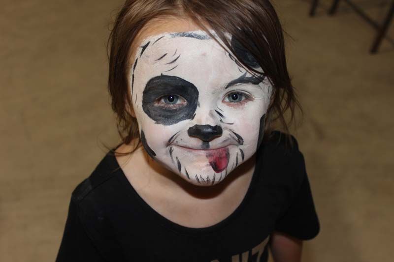 A little girl with her face painted like a panda bear