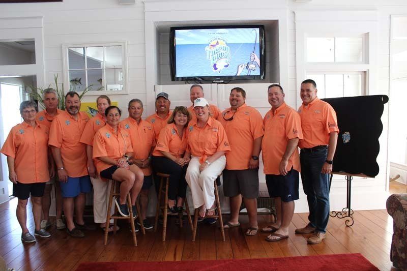 A group of people are posing for a picture in front of a television.