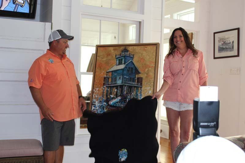 A man and a woman are standing next to a painting of a house