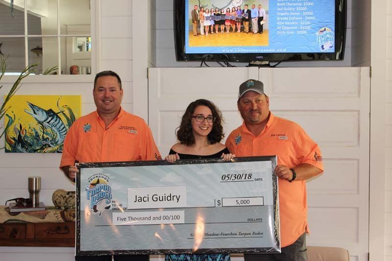 Three people are standing next to each other holding a large check.