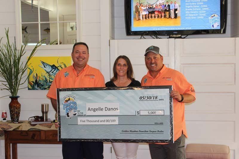 Three people are standing next to each other holding a large check.