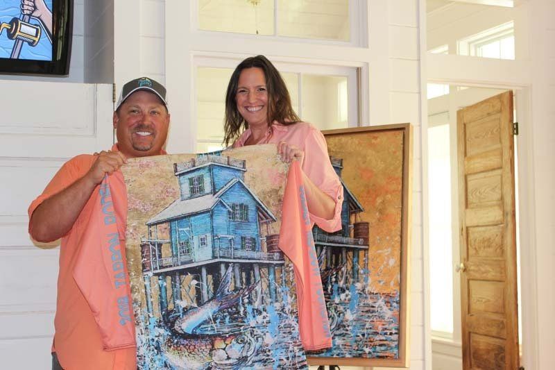 A man and a woman are holding a painting of a house.