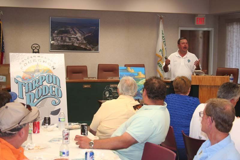 A man is giving a presentation to a group of people in front of a sign that says tampa bay