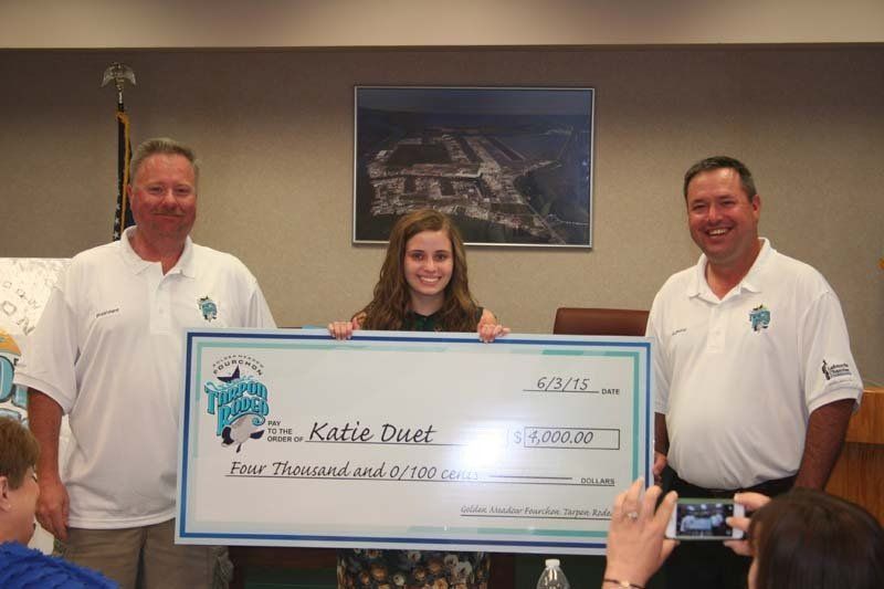 A girl is holding a large check that says katie dust