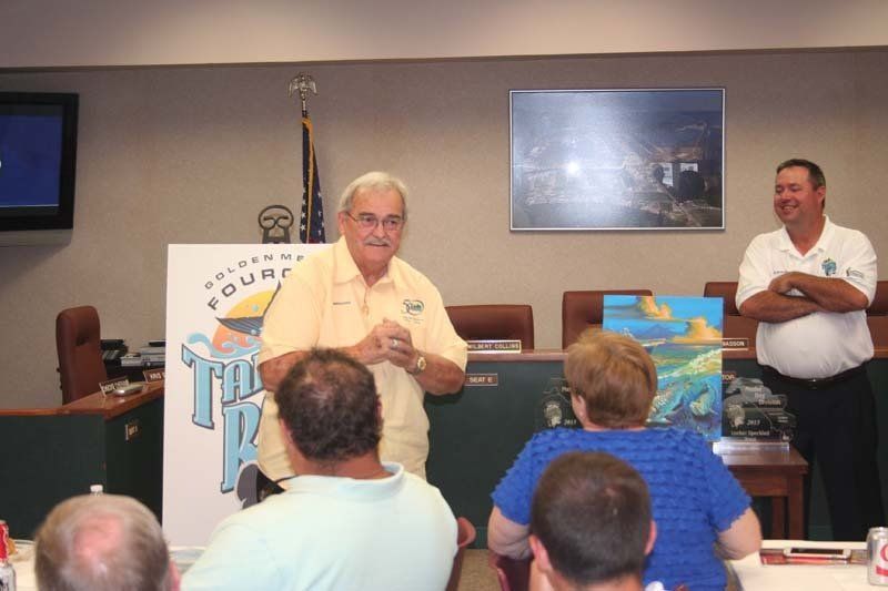 A man in a yellow shirt is giving a presentation to a group of people
