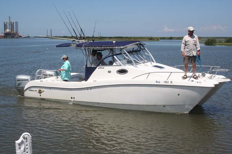 A man stands on the side of a boat with the letters rj on it