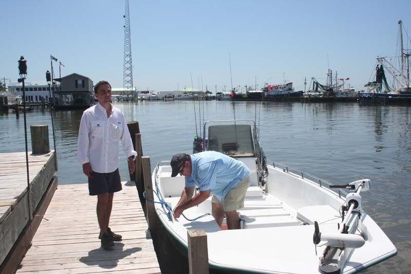 Two men are standing next to a boat in the water