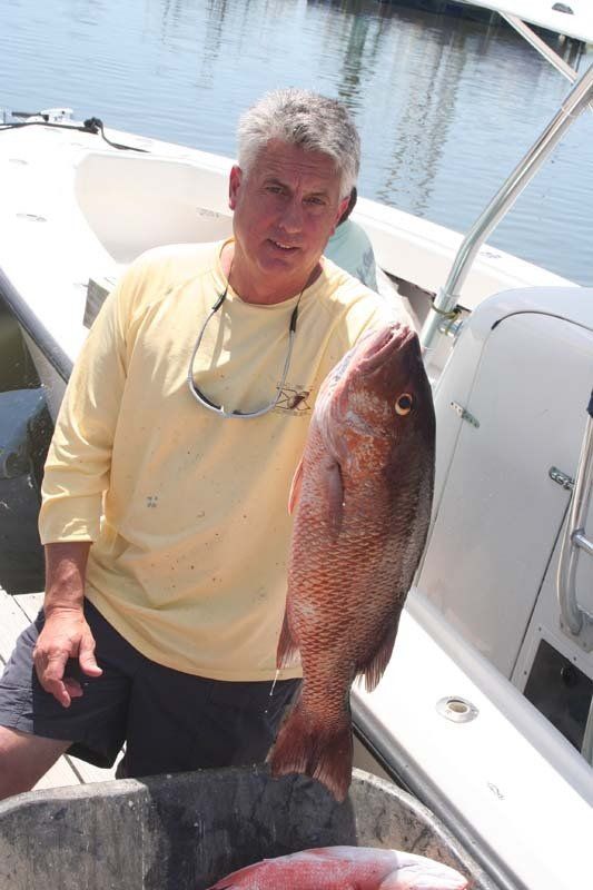 A man is holding a large fish in front of a boat