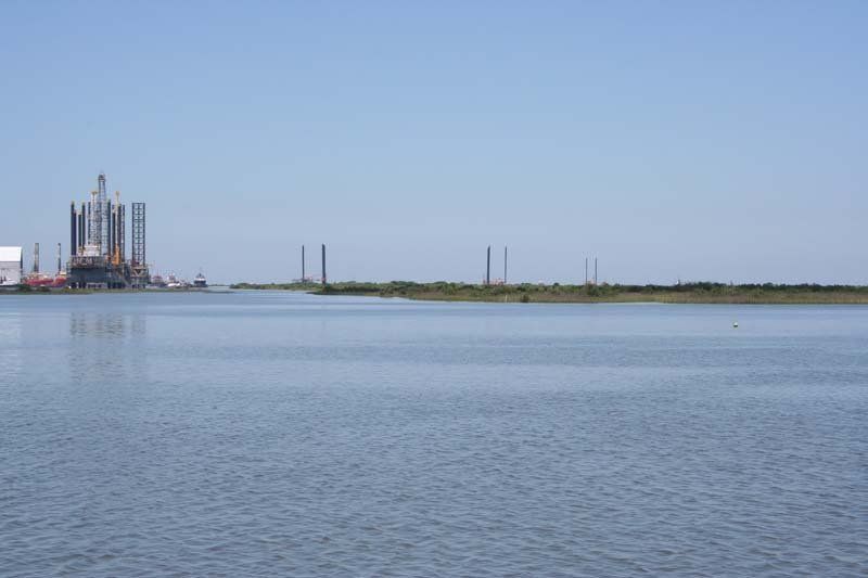 A large body of water with a large oil rig in the distance.