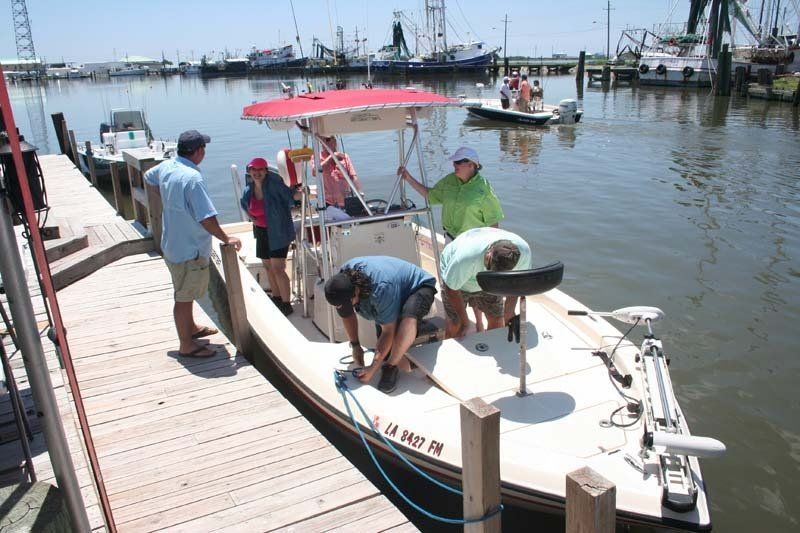 A group of people are loading a boat into the water