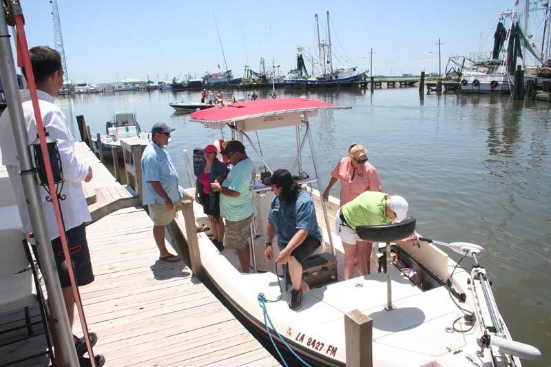 A group of people are standing on a boat with a license plate that says s.j.m. 1657 pk