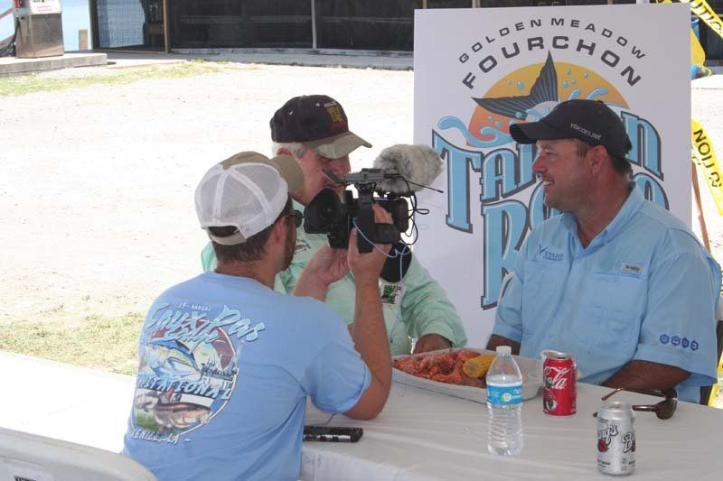 Three men are sitting at a table with a sign that says fourchon on it