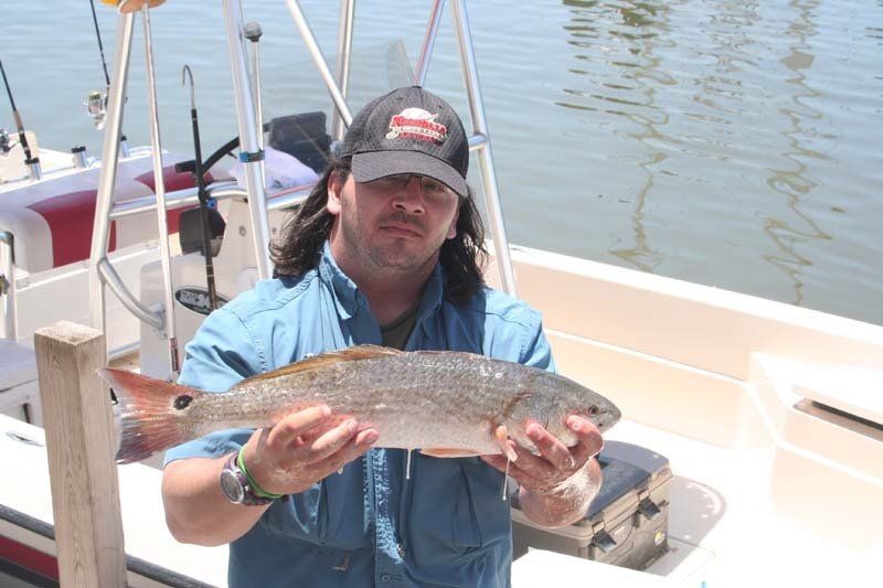 A man is holding a fish in his hands on a boat