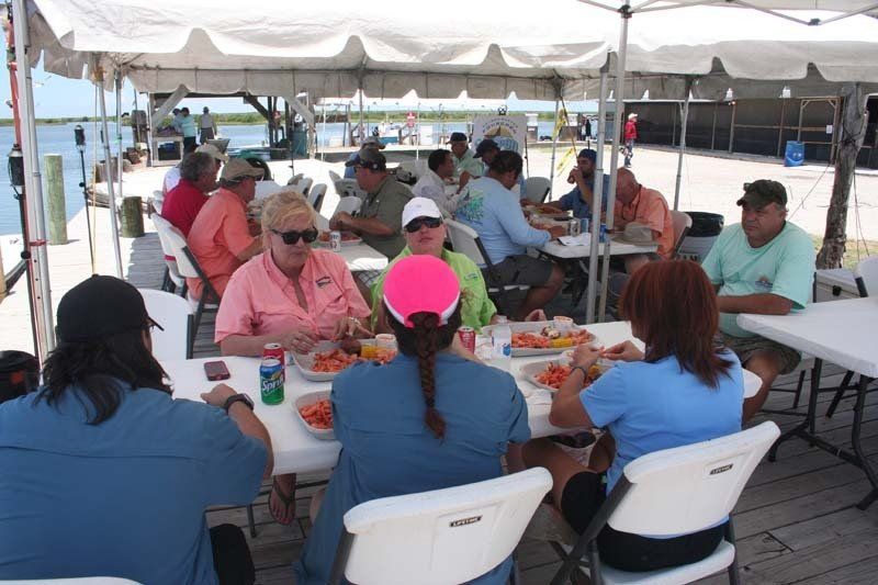 A group of people are sitting at tables under a tent eating food