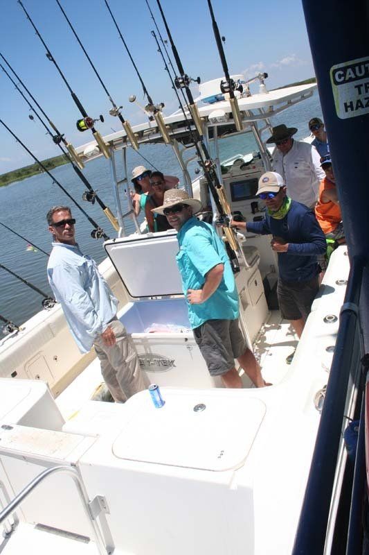 A group of men are on a boat with fishing rods