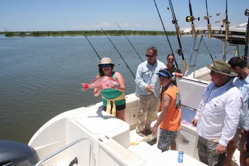 A group of people are fishing on a boat and one of them is holding a fish