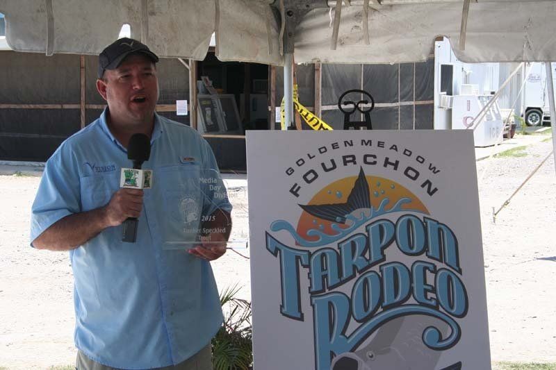 A man stands in front of a sign that says tarpon rodeo