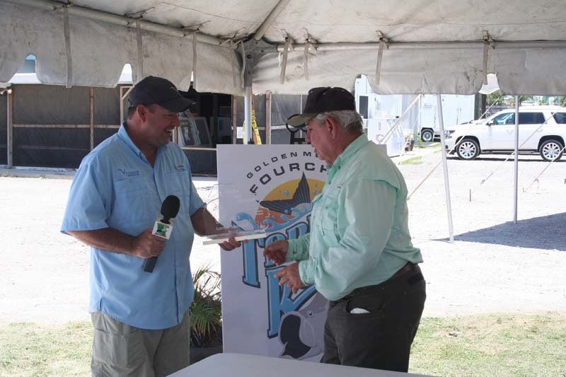 Two men are standing under a tent talking to each other