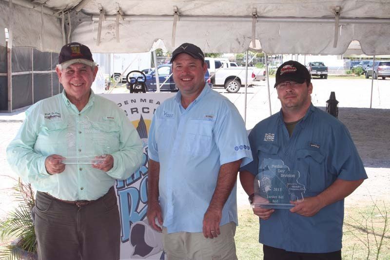 Three men standing under a white tent holding trophies