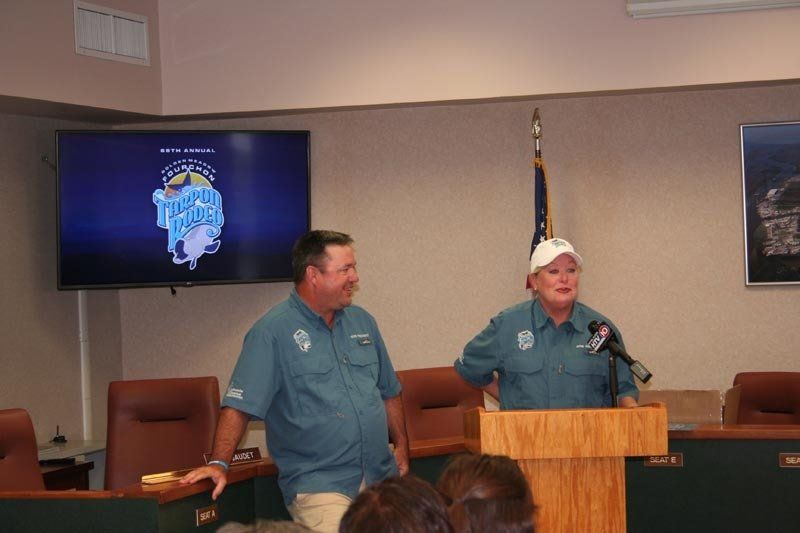 Two men are standing at a podium in front of a television.