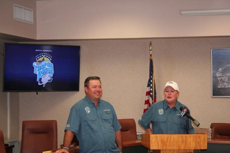Two men are standing at a podium in front of a screen that says fishing lodge