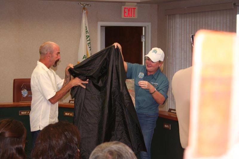 Two men holding a black cloth in front of an exit sign