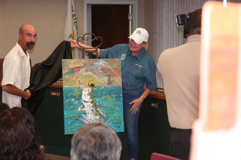 A man is holding a painting of a fish in the water