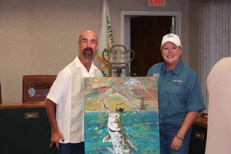 A man and a woman holding a painting of a fish