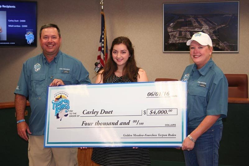 Two men and a woman holding a large check for carley duet