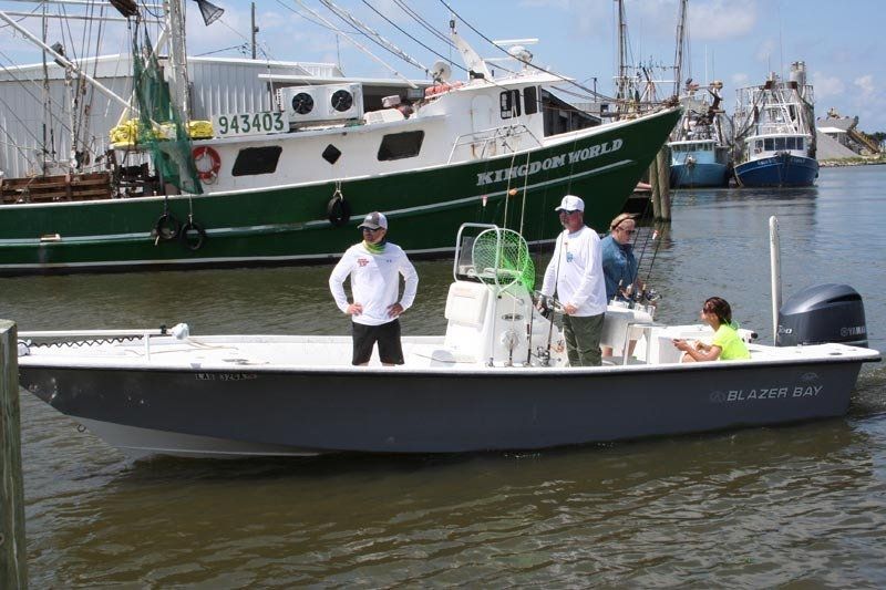 A group of people are standing on a boat with a green boat in the background