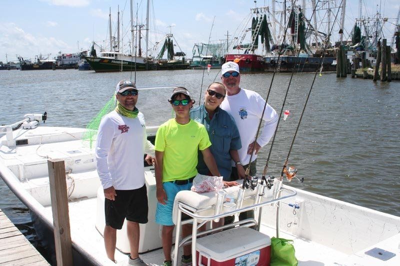 A group of men are standing on a boat in the water.
