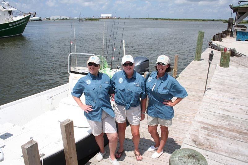 Three women standing on a dock next to a boat
